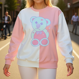 Person wearing a pastel-colored sweatshirt with a teddy bear design on a street.